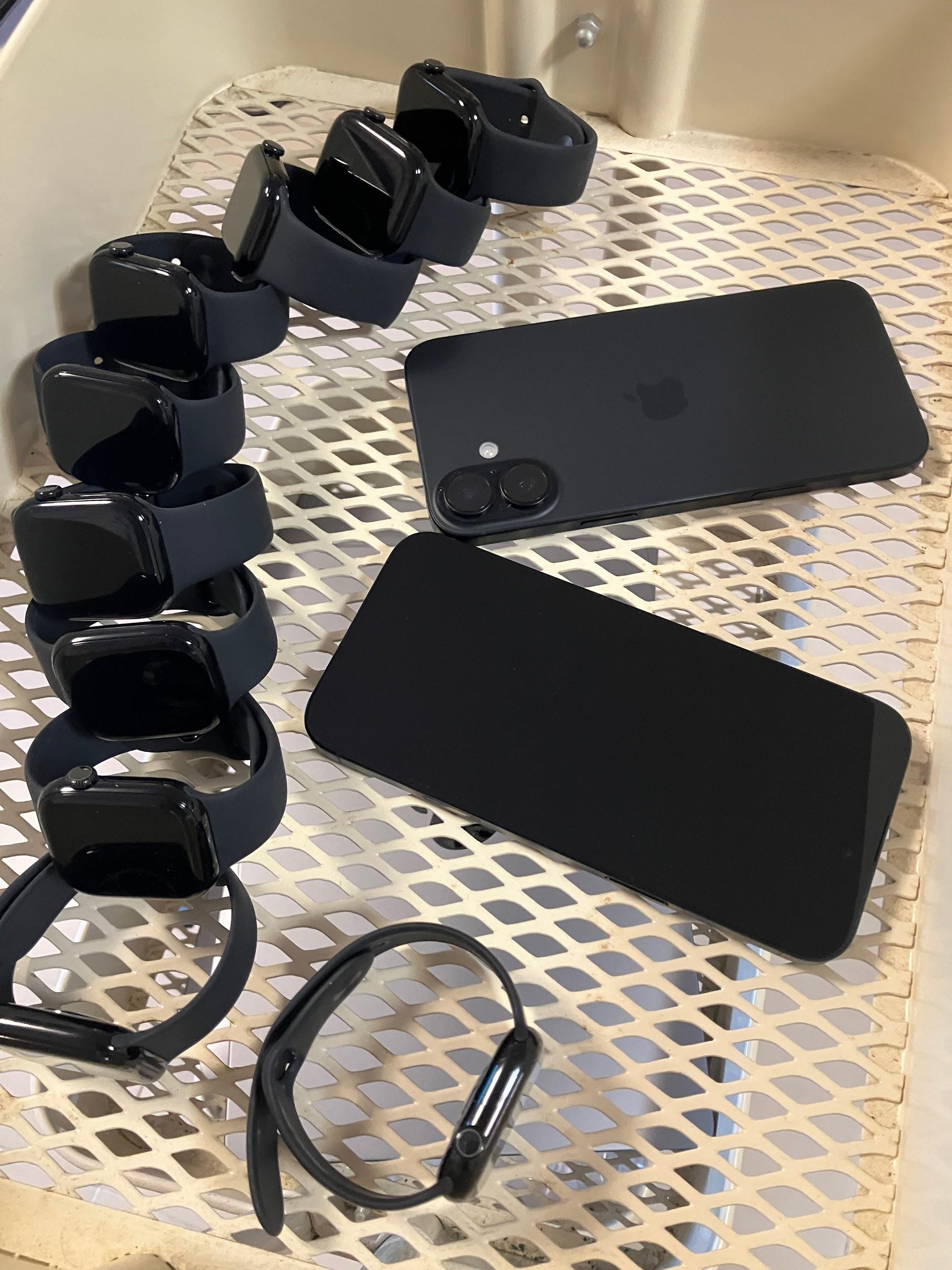 Multiple black smart watches and two black mobile phones arranged for project testing